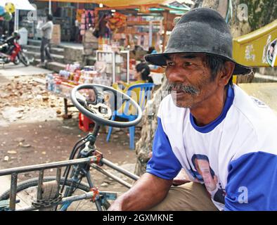 Un uomo anziano seduto sulla sua bicicletta con la vettura laterale fuori da un mercato in attesa di trasportare merci per i clienti a Bukittinggi, Sumatra occidentale, Indonesia. Foto Stock