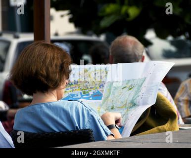 Funchal, Madeira, Portogallo - Febbraio 2016: Persona seduta fuori di un caffè leggendo una mappa della città Foto Stock