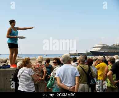 Funchal, Madeira, Portogallo - Febbraio 2016: Guida turistica che spiega la storia della città a un gruppo di turisti. Sullo sfondo c'è una nave da crociera Foto Stock