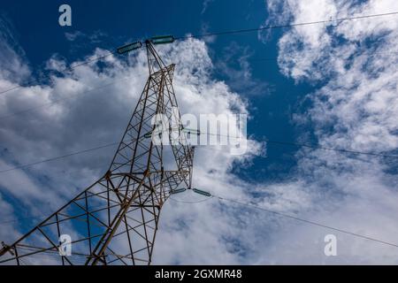 pilone di elettricità sulla rete nazionale contro un cielo blu con nuvole bianche e fluenti, alimentatori, reti elettriche, energia domestica ed elettrica. Foto Stock
