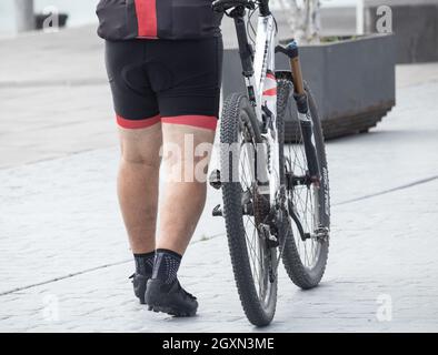 Uomo in età media sovrappeso, ciclista, lycra indossato. MAMIL ( uomo di mezza età in lycra ). Foto Stock