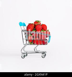 Carrello giocattolo o carrello pieno di grandi fragole rosse mature isolate su sfondo bianco. Concetto di vendita del raccolto di Berry Foto Stock