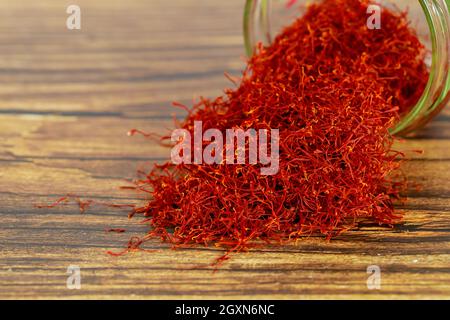 Crocus di zafferano su sfondo rustico in legno. Cucina indiana. Foto Stock