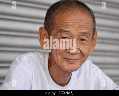 Vecchio skinny resourceful positivo malese cinese risciò driver con visse-in faccia e grinzed fronte guarda lo spettatore. Foto Stock