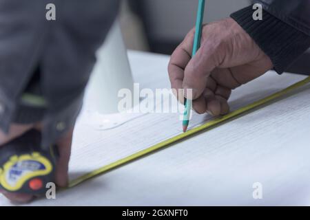 Carpenter lavoratore di misurazione di distanza per la perforazione di fori nel nuovo arredamento Foto Stock