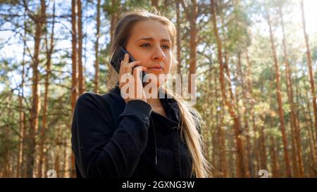 Ritratto di bella giovane donna con smartphone in pineta. Foto Stock