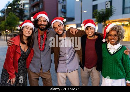 Ritratto di gruppo di amici allegri multirazziali che indossano il cappello di Babbo Natale a natale Foto Stock