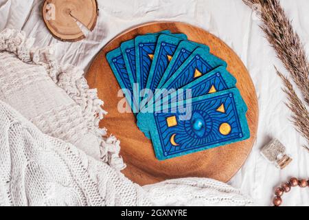 Mazzo di carte Tarocchi fiondati su vassoio di legno su tela bianca con cuscini, copriletto e spikelets. Vista dall'alto. Minsk, Bielorussia - 09.27.2021 Foto Stock