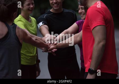 Gruppo di corridori sani dando alta cinque per ogni altro mentre celebriamo il successo dopo una sessione di formazione. Foto Stock
