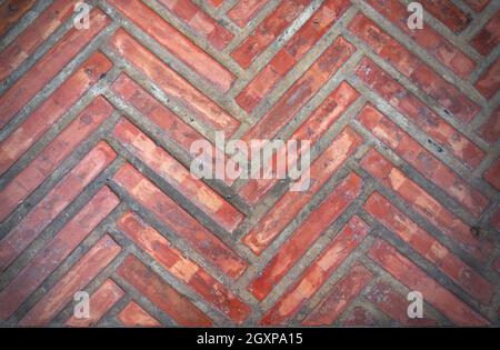 Pavimento piastrellato in mattoni rosso-arancio con motivo a zigzag Foto Stock