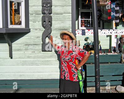 Nanny Chris, una guida nel villaggio termale di Whaka a Rotorua, Nuova Zelanda, spiega il significato culturale della scultura Maori sul lato dell'edificio. Nanny Chris lavora e vive nel villaggio che fa parte della zona vulcanica di Taupo e si trova nella caldera di un vulcano. Gli scambi interculturali tra gli abitanti del villaggio e i visitatori sono in corso da decenni. Foto Stock