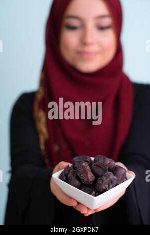 donna musulmana moderna che tiene un piatto pieno di datteri dolci sul tempo di iftar in ramadan kareem islamico sano concetto di cibo Foto Stock