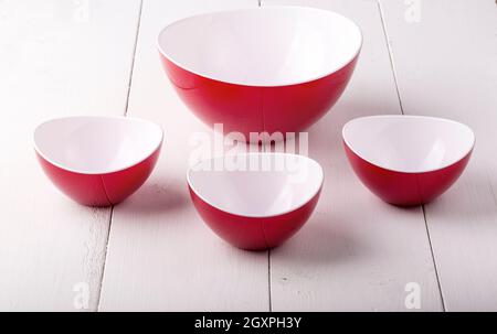 Una ciotola di insalata rossa vuota e tre tazze su a. tavolo di legno bianco Foto Stock