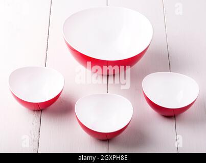 Una ciotola di insalata rossa vuota e tre tazze su a. tavolo di legno bianco Foto Stock