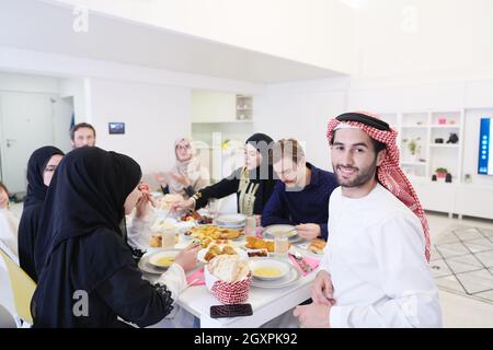 Giovane uomo arabo con cena Iftar con famiglia musulmana mangiare cibo tradizionale durante il mese di festa Ramadan a casa. Il pasto Islamico Halal e D. Foto Stock