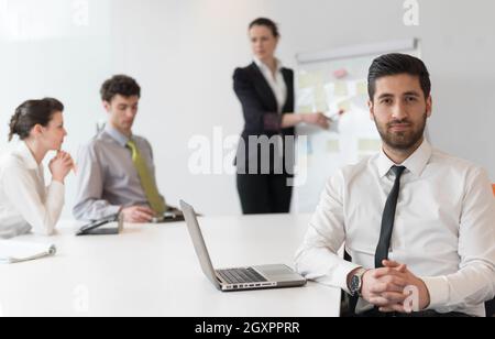 Ritratto di giovane arabo moderno business man con la barba in ufficio, gruppo di gente di affari sulla riunione rendendo la presentazione in background Foto Stock