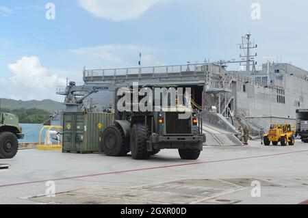 SANTA RITA, Guam (settembre 9, 2021) Seabees assegnato a Naval Mobile Construction Battaglione (NMCB) 1, distaccamento Guam, ha utilizzato un carrello elevatore a forche per caricare un contenitore di spedizione Lightweight Water Purification Systems (LWPS) sulla Spearhead-class trasporto rapido USNS City di Bismarck (T-EPF-9) per il trasporto verso la Repubblica di Palau. Il LWPS è progettato per convalidare le capacità di produzione di acqua potabile Seabee per supportare le attività della flotta. L'NMCB 1 è stato implementato in avanti per eseguire lavori di costruzione, assistenza umanitaria, cooperazione per la sicurezza del teatro e supportare la manovra della flotta nelle aree della 7a flotta degli Stati Uniti Foto Stock