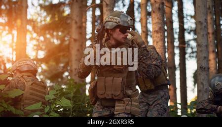 il soldato moderno della guerra sta mostrando i segnali tattici della mano per dare silenziosamente ordini e i generatori per l'ambiente della foresta della squadra Foto Stock