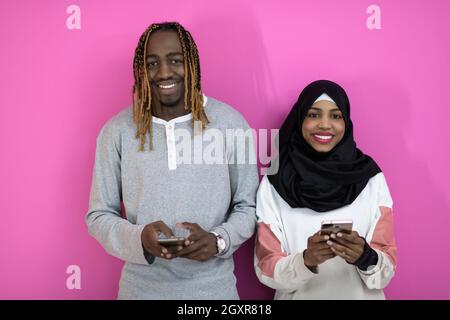 Felice giovane africano coppia americana di ridere utilizzando applicazioni smartphone isolato in rosa di sfondo per studio, allegro nero amici gli utenti mobile di contenimento ph Foto Stock