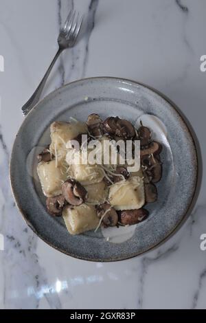 Ravioli al formaggio in salsa cremosa toscana con funghi cremini saltati Foto Stock
