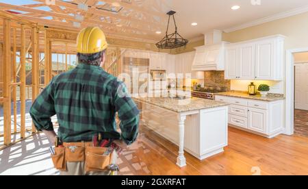 Contractor in piedi nella cornice di costruzione della cucina personalizzata anteriore che si laurea in costruzione finita. Foto Stock