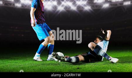 Azione di concorrenza di correre e saltare il duello dei giocatori di calcio al pallone da calcio stadium di notte Foto Stock