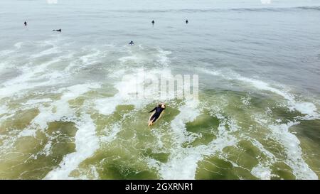 Uomo maturo pagaiare, sdraiato su una tavola da surf - uomo senior Sportive surf nell'oceano Pacifico, in una giornata di sole con cielo blu e onde trasparenti Foto Stock
