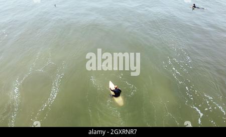Uomo maturo pagaiare, sdraiato su una tavola da surf - uomo senior Sportive surf nell'oceano Pacifico, in una giornata di sole con cielo blu e onde trasparenti Foto Stock