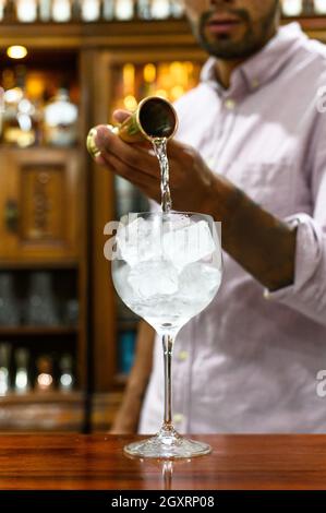 Versare un cocktail in un bicchiere di ghiaccio Foto Stock
