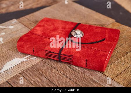 Libro in pelle rossa lavorato a mano con filo nero su assi in legno Foto Stock