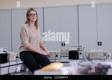 Ritratto di giovane e bella studentessa seduta sul tavolo al laboratorio di elettronica classroom Foto Stock