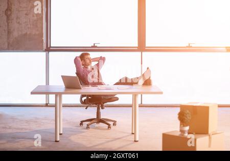 Giovane imprenditore casual prendendo una pausa sul sito in costruzione mentre il controllo dei documenti e del flusso di lavoro aziendale utilizzando un computer portatile con luce solare tramite Foto Stock