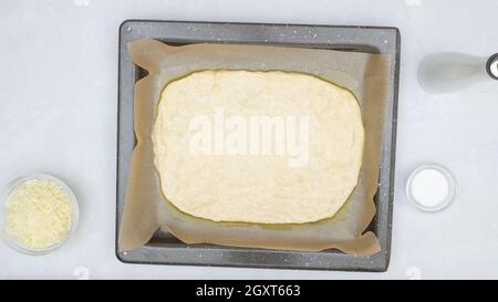 Pane piatto con mozzarella e ricetta graduale. L'impasto del pane si avvicina alla griglia da forno, vista dall'alto Foto Stock