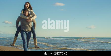 Gli uomini dando Piggy Back corse al tramonto sul mare, tempo di autunno Foto Stock