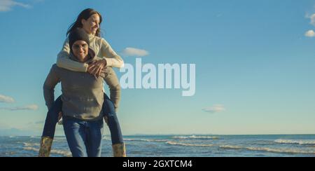 Gli uomini dando Piggy Back corse al tramonto sul mare, tempo di autunno Foto Stock