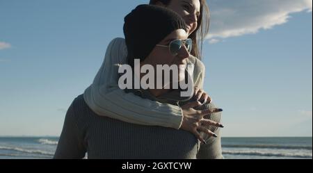 Gli uomini dando Piggy Back corse al tramonto sul mare, tempo di autunno Foto Stock