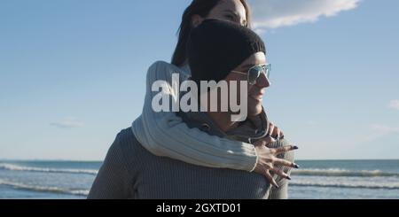 Gli uomini dando Piggy Back corse al tramonto sul mare, tempo di autunno Foto Stock