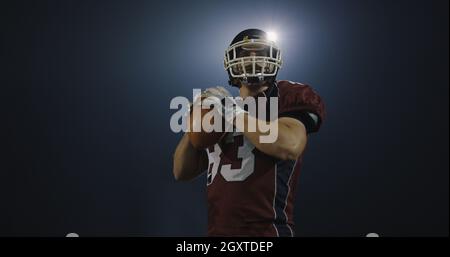 Giocatore di football americano rugby gettando la sfera su sfondo nero Foto Stock