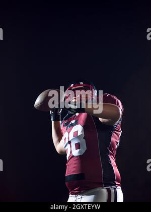 Giocatore di football americano rugby gettando la sfera su sfondo nero Foto Stock