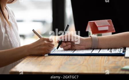 primo piano le mani di vista di uomo d'affari che firmano i documenti domestici di leasing ed hanno un appartamento chiavi sul lavoro di ufficio Foto Stock