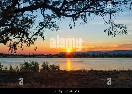 Sole all'orizzonte al tramonto sul fiume Pentecoste presso la stazione di Home Valley, Gibb River Road, Western Australia, WA, Australia Foto Stock