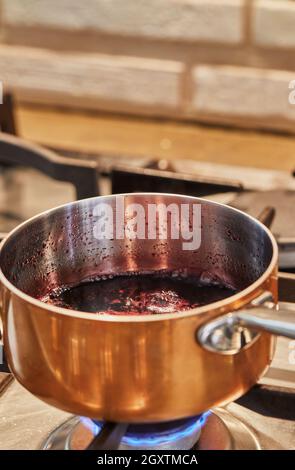 Pentola di rame a fuoco basso su stufa per fare la salsa. Foto Stock