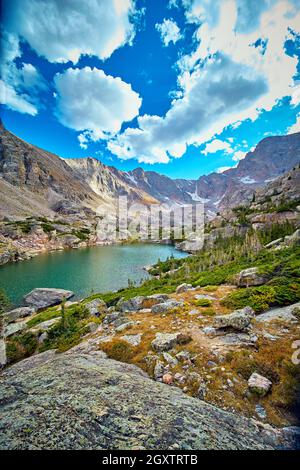 Lago in montagne rocciose con roccia lichen in primo piano Foto Stock