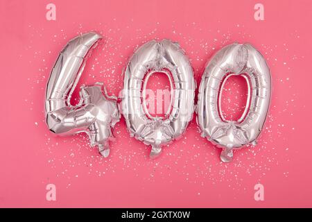 Da sopra di palloncini d'argento lucido che mostrano numero 400 quattrocento sfondo rosa con glitter sparsi Foto Stock