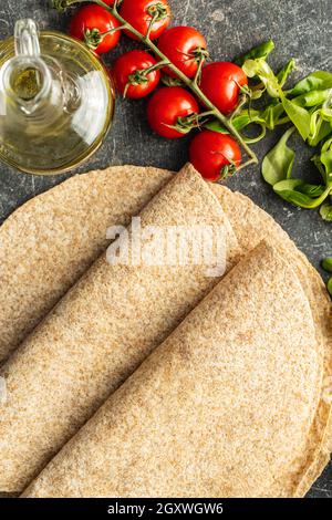 Tortilla di grano intero avvolge su tavolo da cucina. Vista dall'alto. Foto Stock