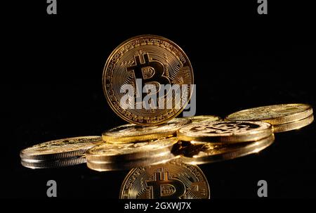Leader nella criptovaluta bitcoin BTC su una cima di monete contro la superficie nera specchio. Primo piano moneta d'oro con logo bitcoin. Un mucchio di decentralizzati di Foto Stock