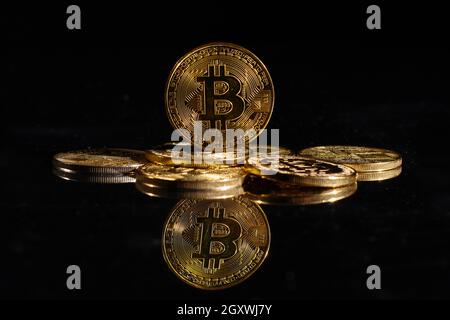 Leader nella criptovaluta bitcoin BTC su una cima di monete contro la superficie nera specchio. Primo piano moneta d'oro con logo bitcoin. Un mucchio di decentralizzati di Foto Stock