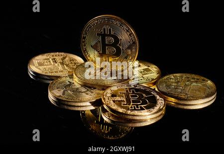Leader nella criptovaluta bitcoin BTC su una cima di monete contro la superficie nera specchio. Primo piano moneta d'oro con logo bitcoin. Un mucchio di decentralizzati di Foto Stock