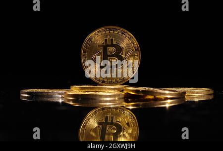 Leader nella criptovaluta bitcoin BTC su una cima di monete contro la superficie nera specchio. Primo piano moneta d'oro con logo bitcoin. Un mucchio di decentralizzati di Foto Stock