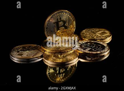 Leader nella criptovaluta bitcoin BTC su una cima di monete contro la superficie nera specchio. Primo piano moneta d'oro con logo bitcoin. Un mucchio di decentralizzati di Foto Stock
